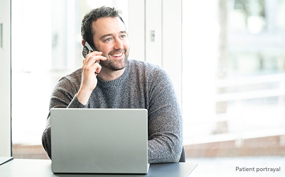 A man on the phone sitting in front of a laptop
